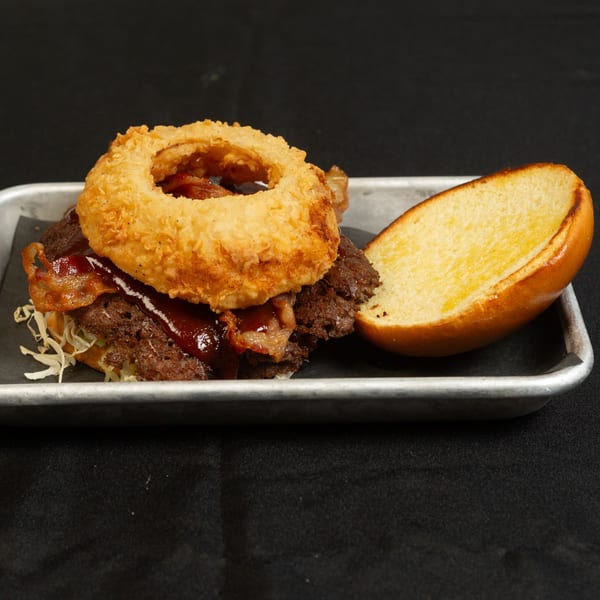 The Roadhouse's open-faced burger with bacon, BBQ sauce, shredded lettuce, and a crispy onion ring.