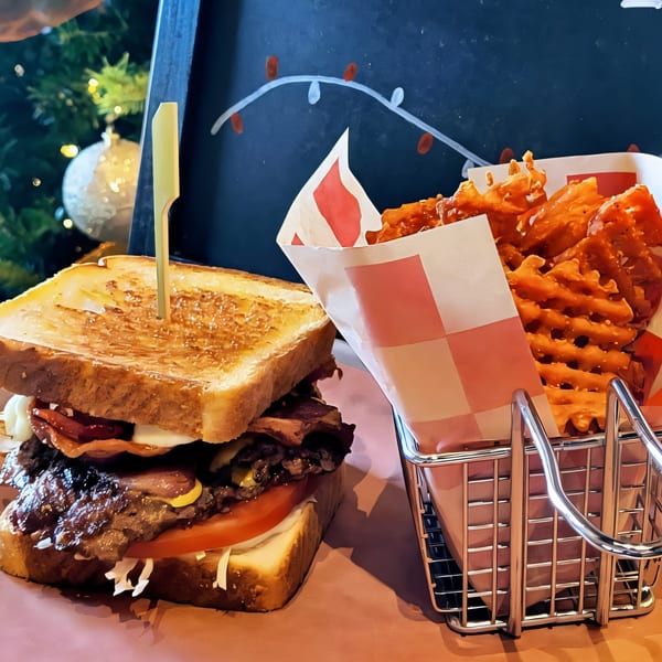 A Roadhouse burger with waffle fries in a metal basket, with a Christmas tree in the background.