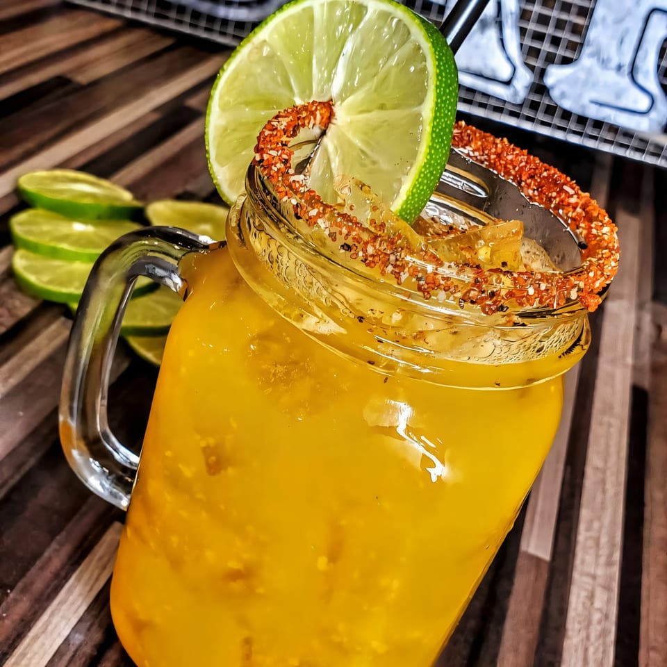 A Roadhouse sports-bar drink in a mason jar, garnished with a lime and chili-salt rim.