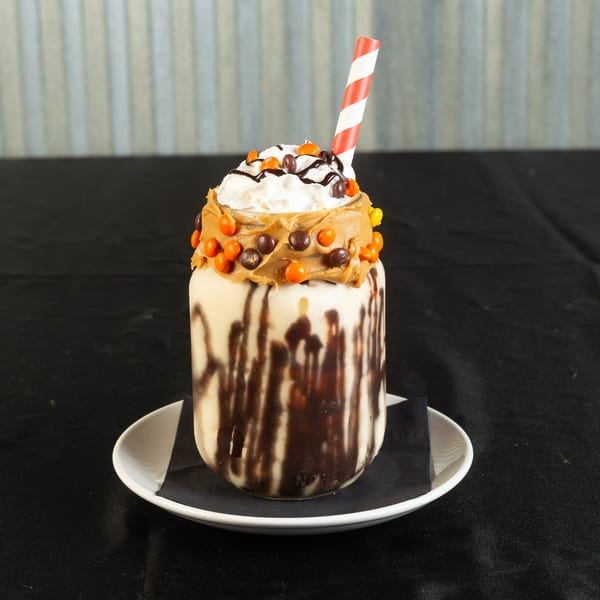 A Roadhouse milkshake in a mason jar, topped with whipped cream, peanut butter, and candies.
